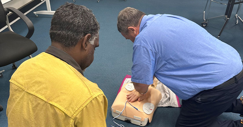 two men practicing CPR on a manikin